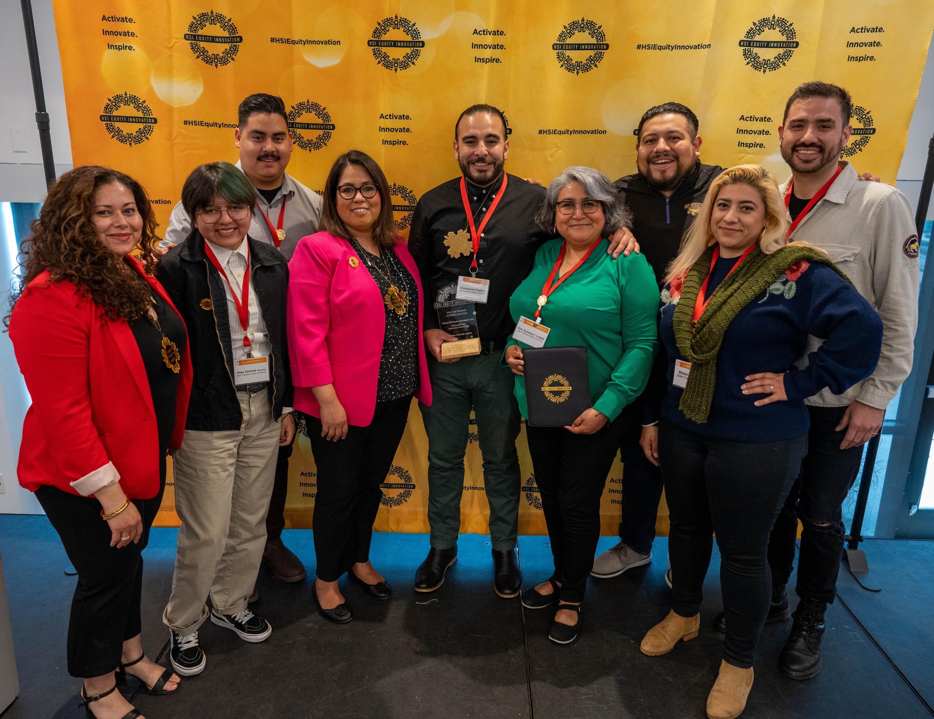 Ten Hub team members and partners posing in front of an HSI Equity Innovation banner, one holding an award.